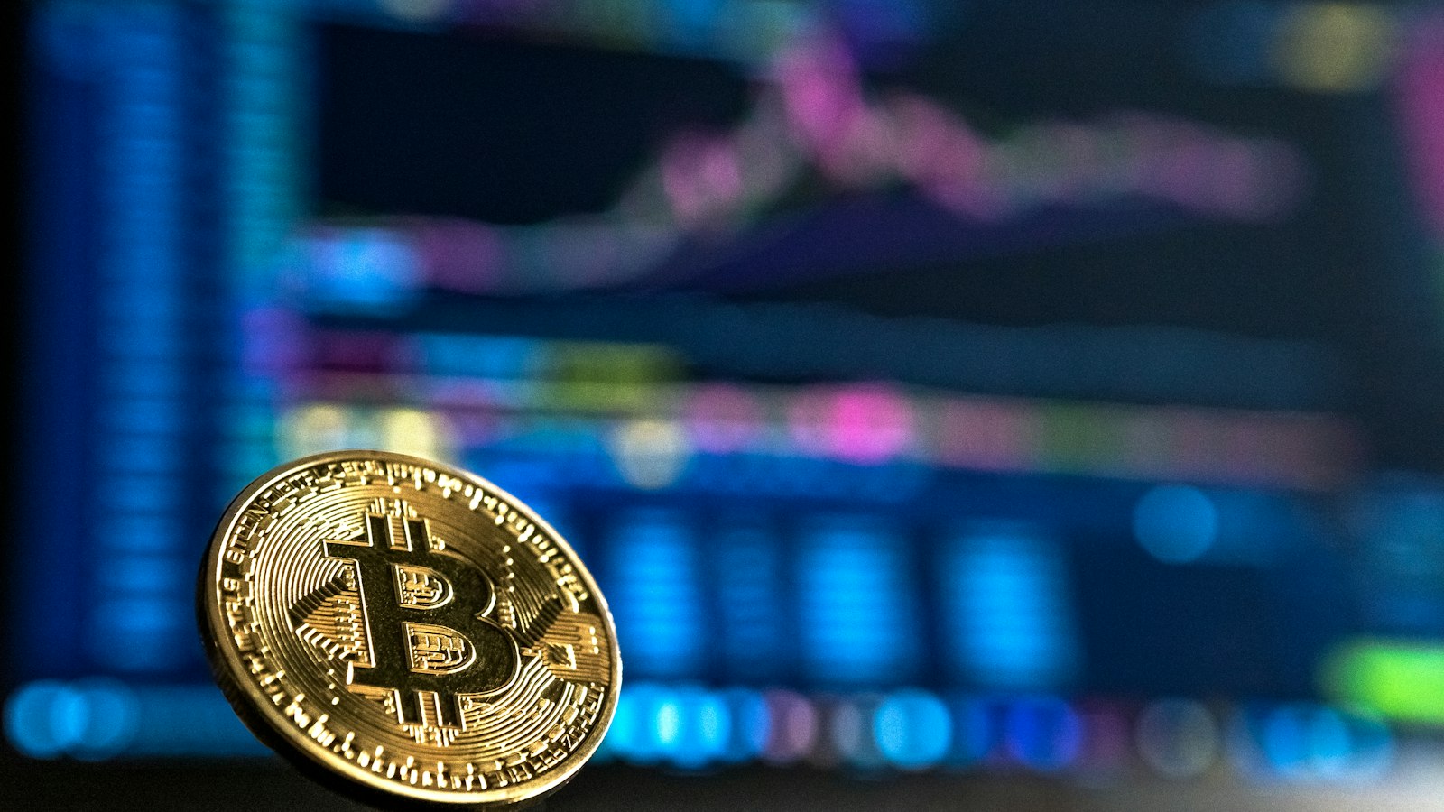 Gold Bitcoin coin in front of a trading chart