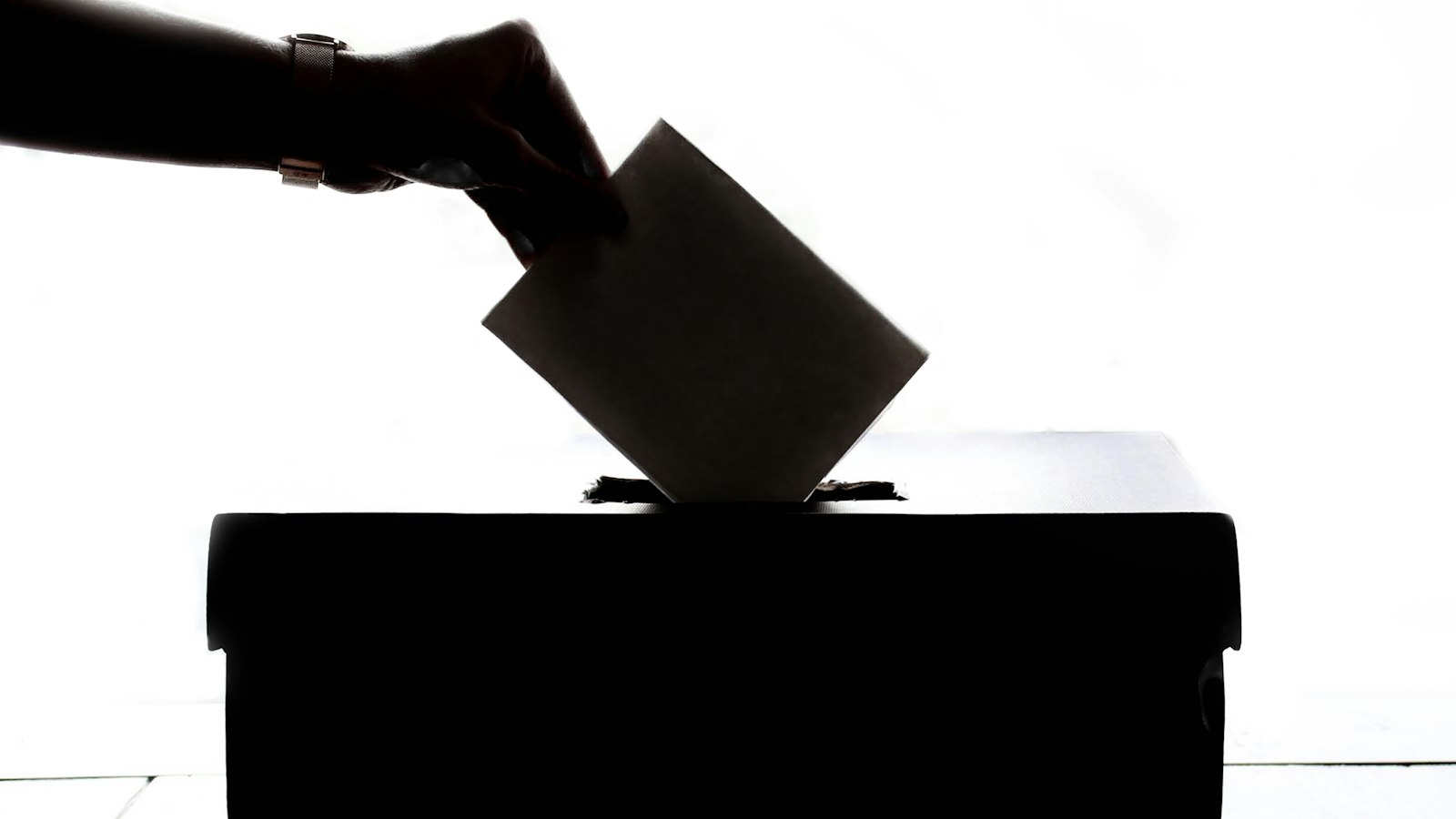 Hand dropping a ballot into a voting box