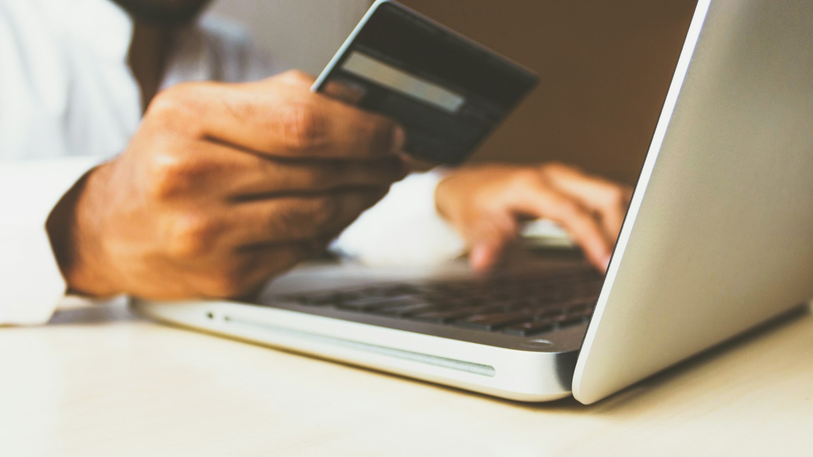Person paying online with a card on a laptop